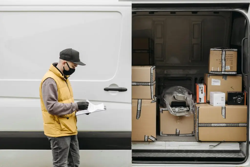 delivery guy standing near his delivery bus full of packages